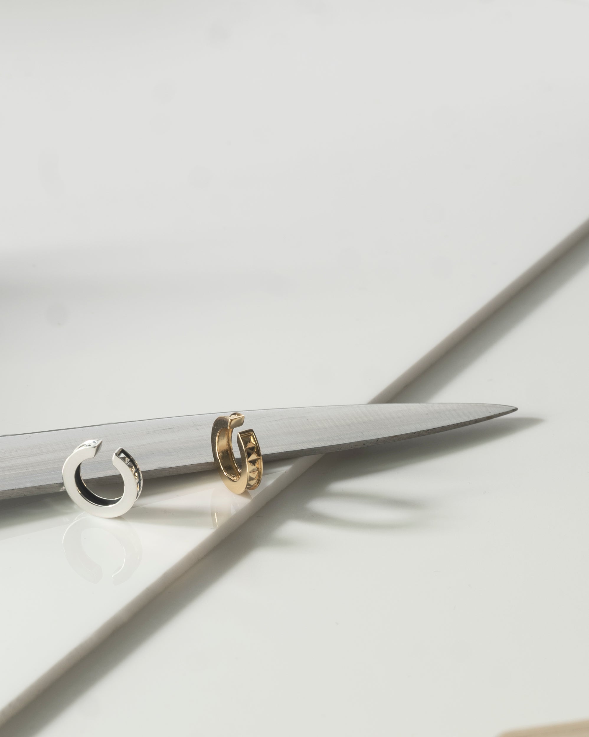 gold and silver earcuff on white reflective surface with knife edge