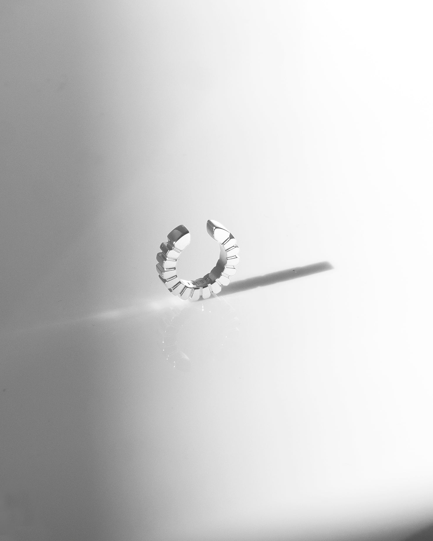 geometric chic silver ear cuff ridged on light grey reflective background with sadow
