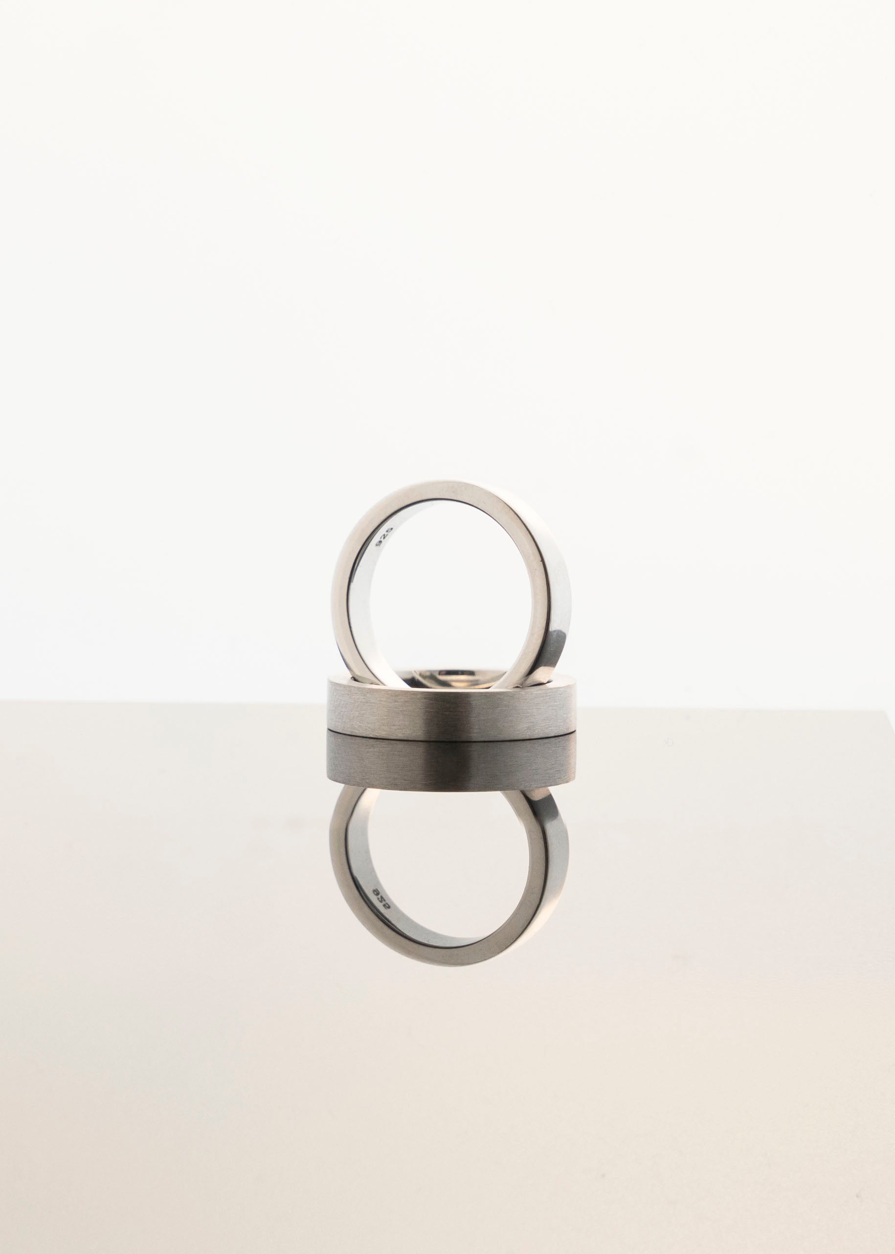 polished and rings in silver reflecting on a mirrored surface