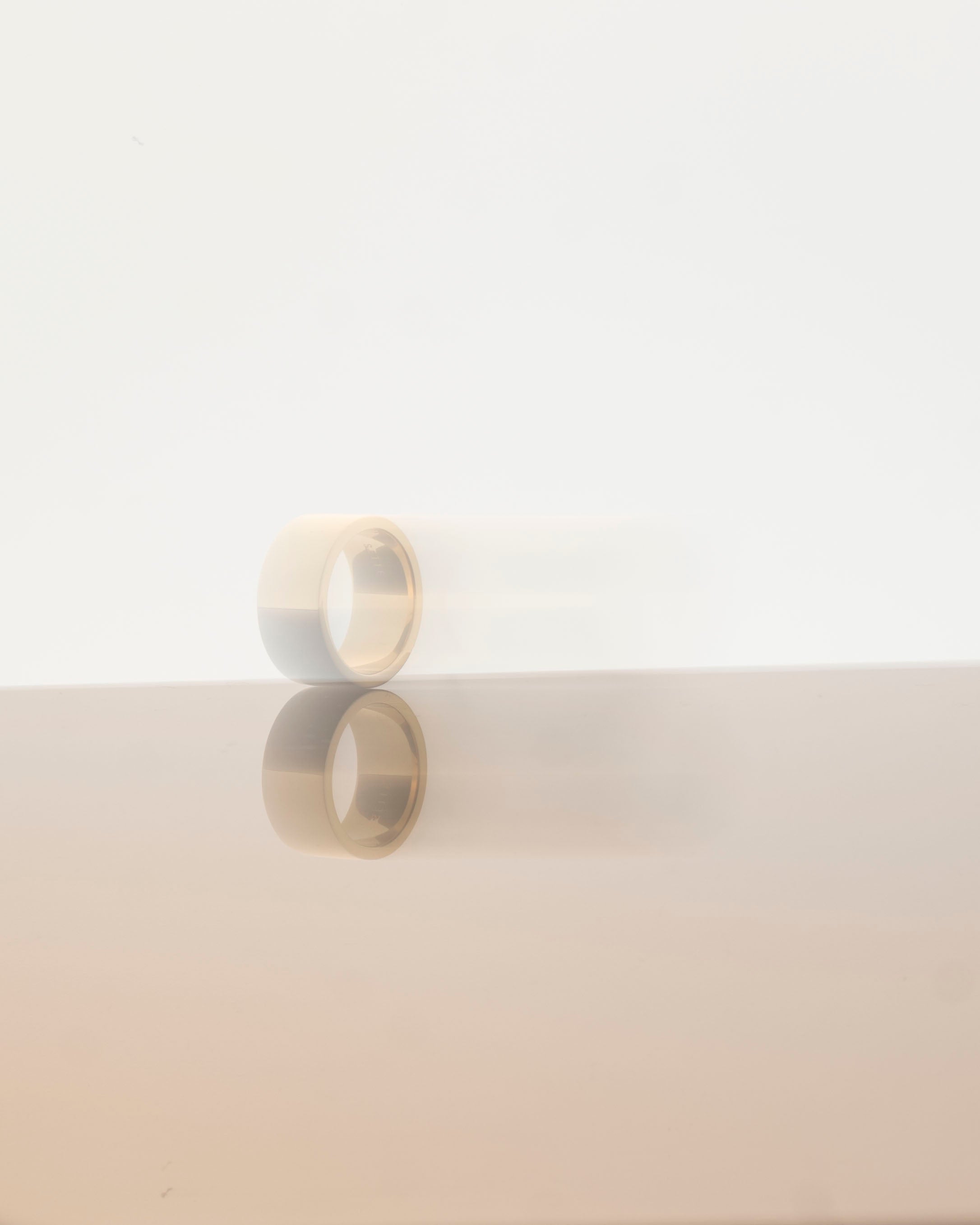 unisex band ring gold on light grey reflective background with blurred effect