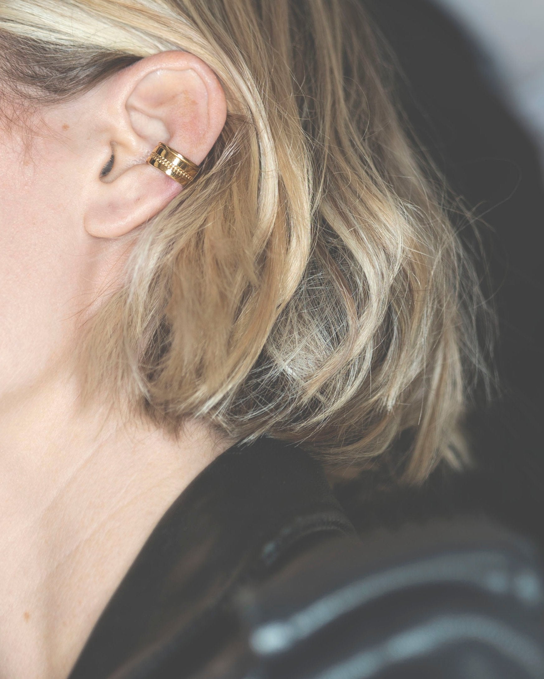 thick gold ear cuff on model with blonde ruffled hair and black leather jacket