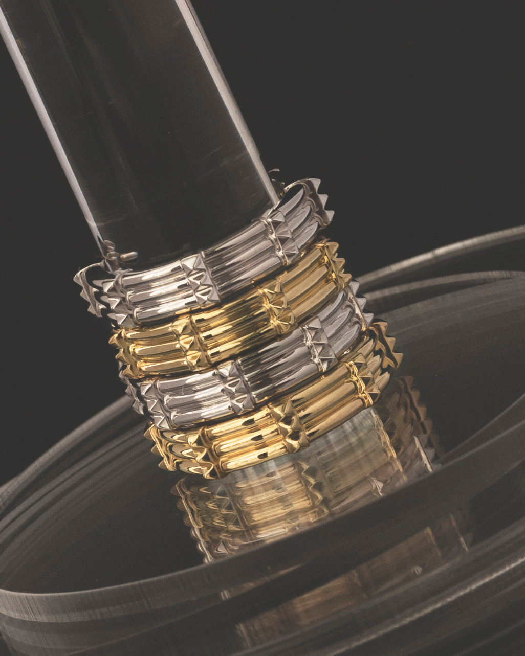 studio sette gold and silver hoop earrings on perspex podium against black background closeup