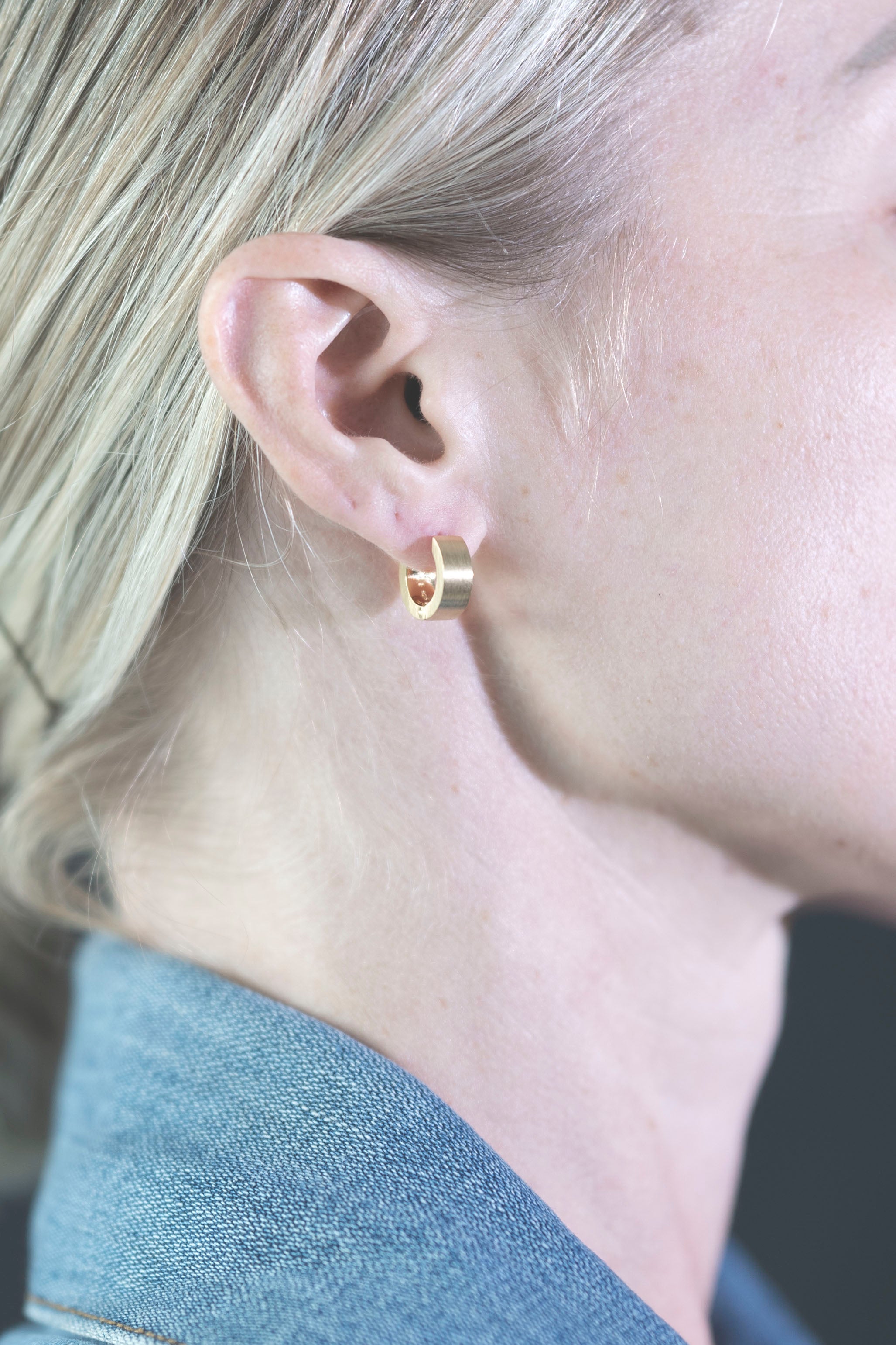 unisex small gold hoop brushed on ear closeup model wearing denim collar
