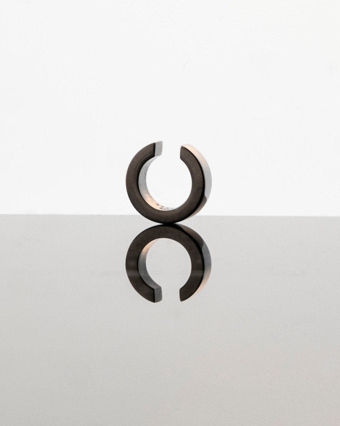 black ear cuff reflecting on mirror surface light grey