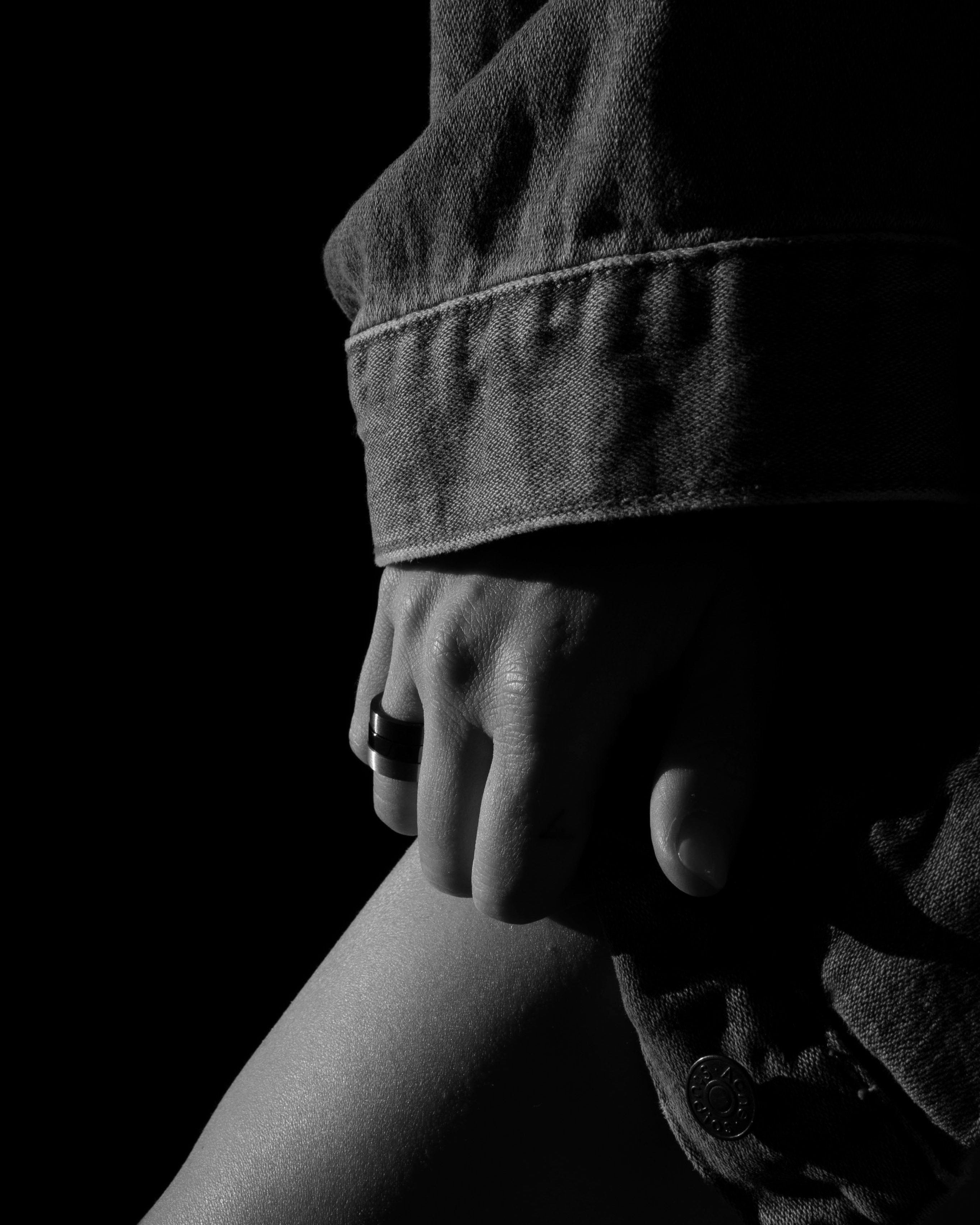 studiosette black and silver band rings stacked on hand leaning on leg model wearing denim jacket monochrome