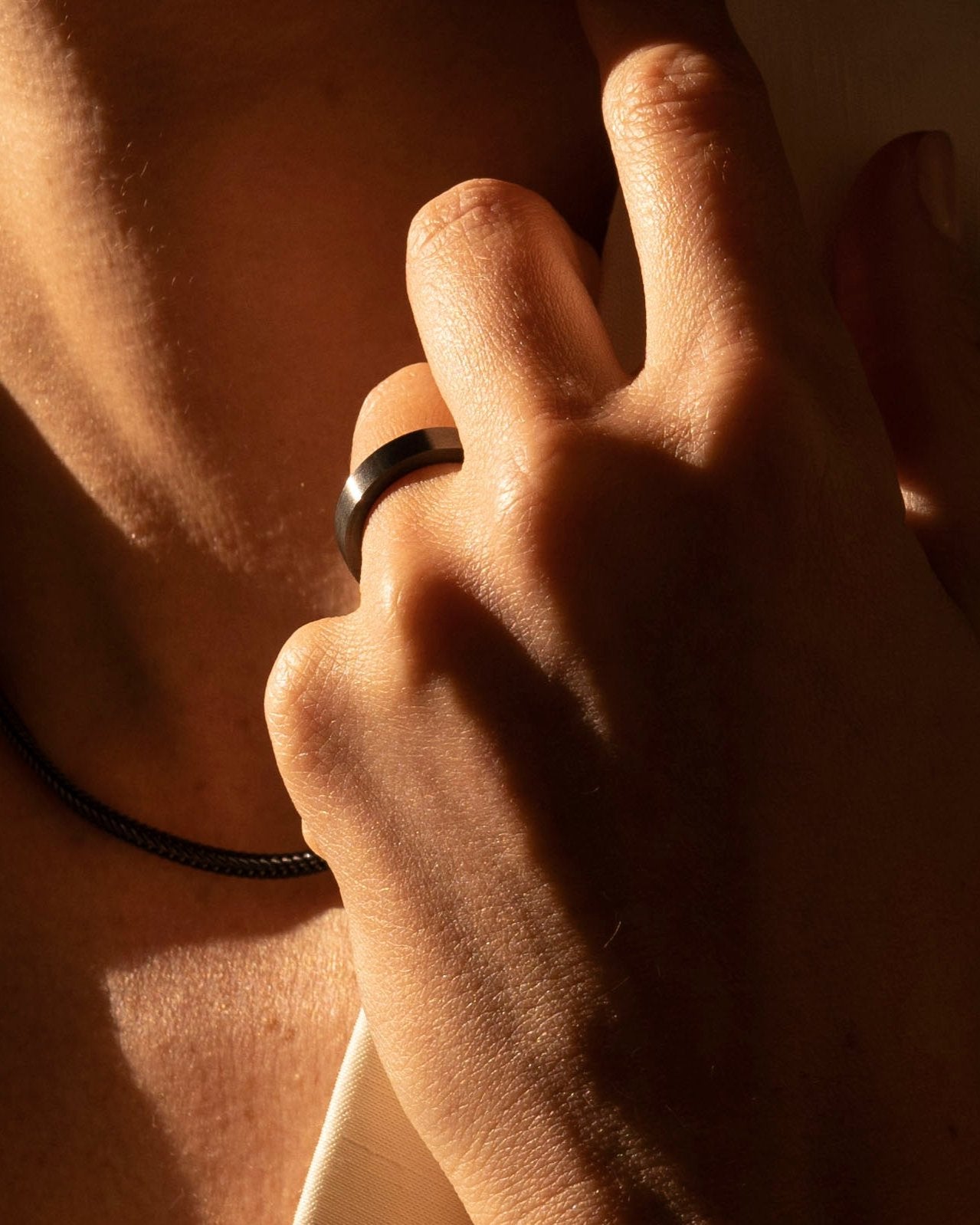 studio sette black ruthenium simple band ring closeup on model ring finger in evening sunshine