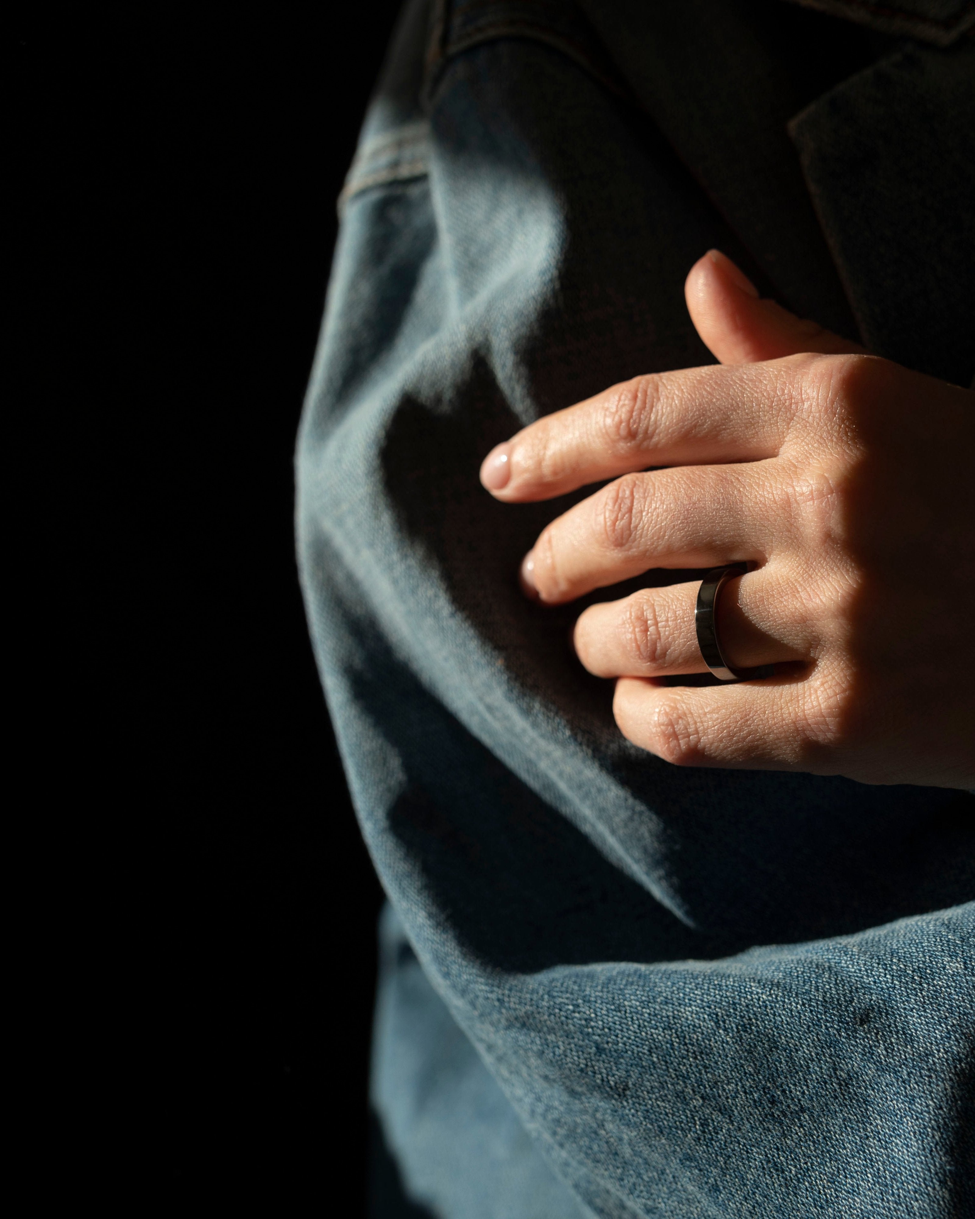 black band ring closeup on hand resting on denim jacket
