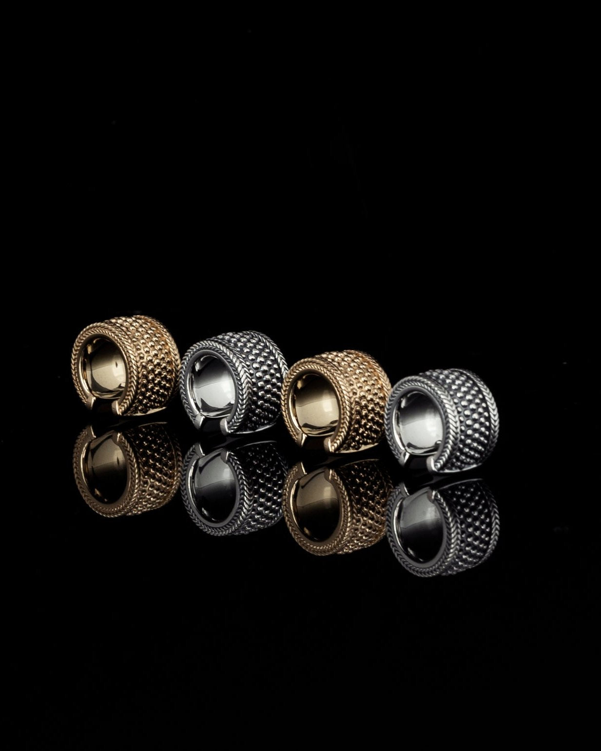 silver and gold ear cuffs reflecting on black mirror surface
