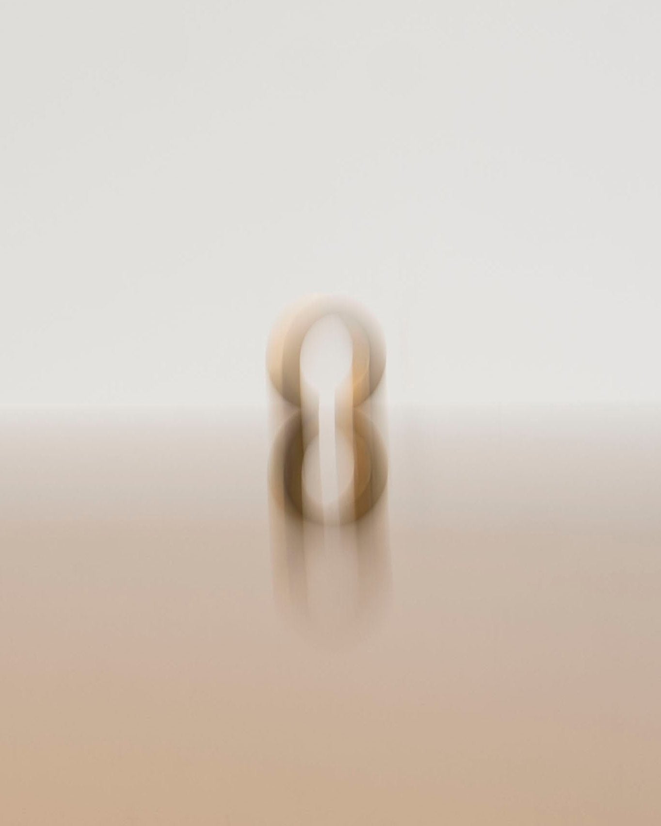 gold ear cuff on creamy white reflective background with blur effect