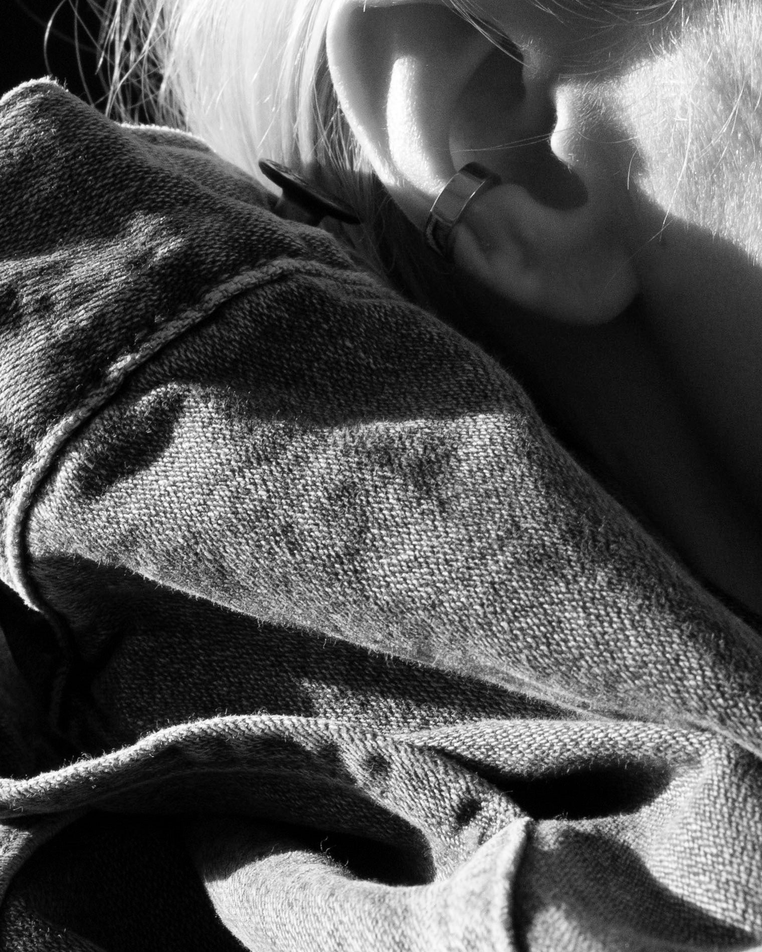 gold ear cuff monochrome on model ear closeup with denim sleeve