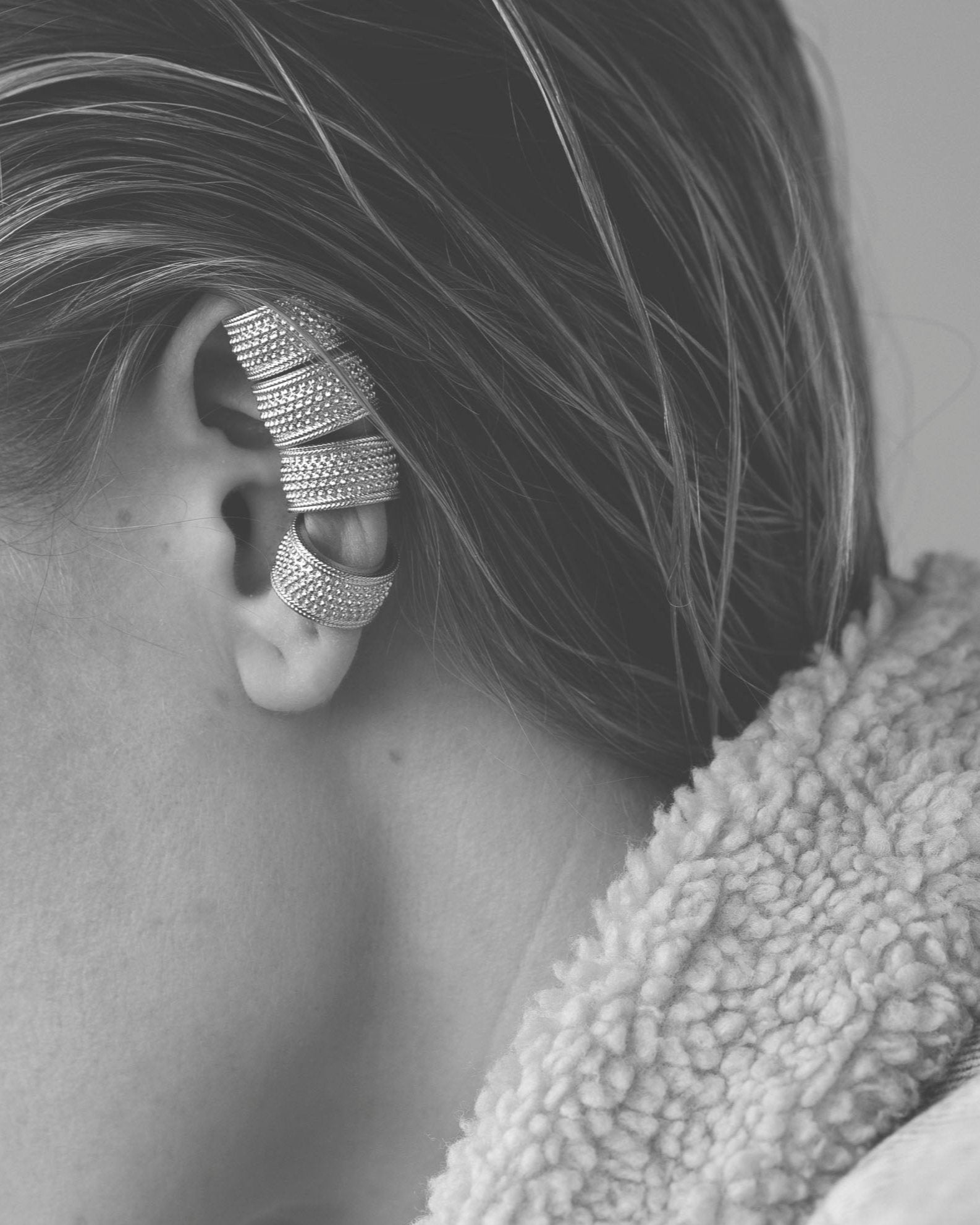 ear cuffs stacked on ear four in a row on model's ear, wearing shearling collar