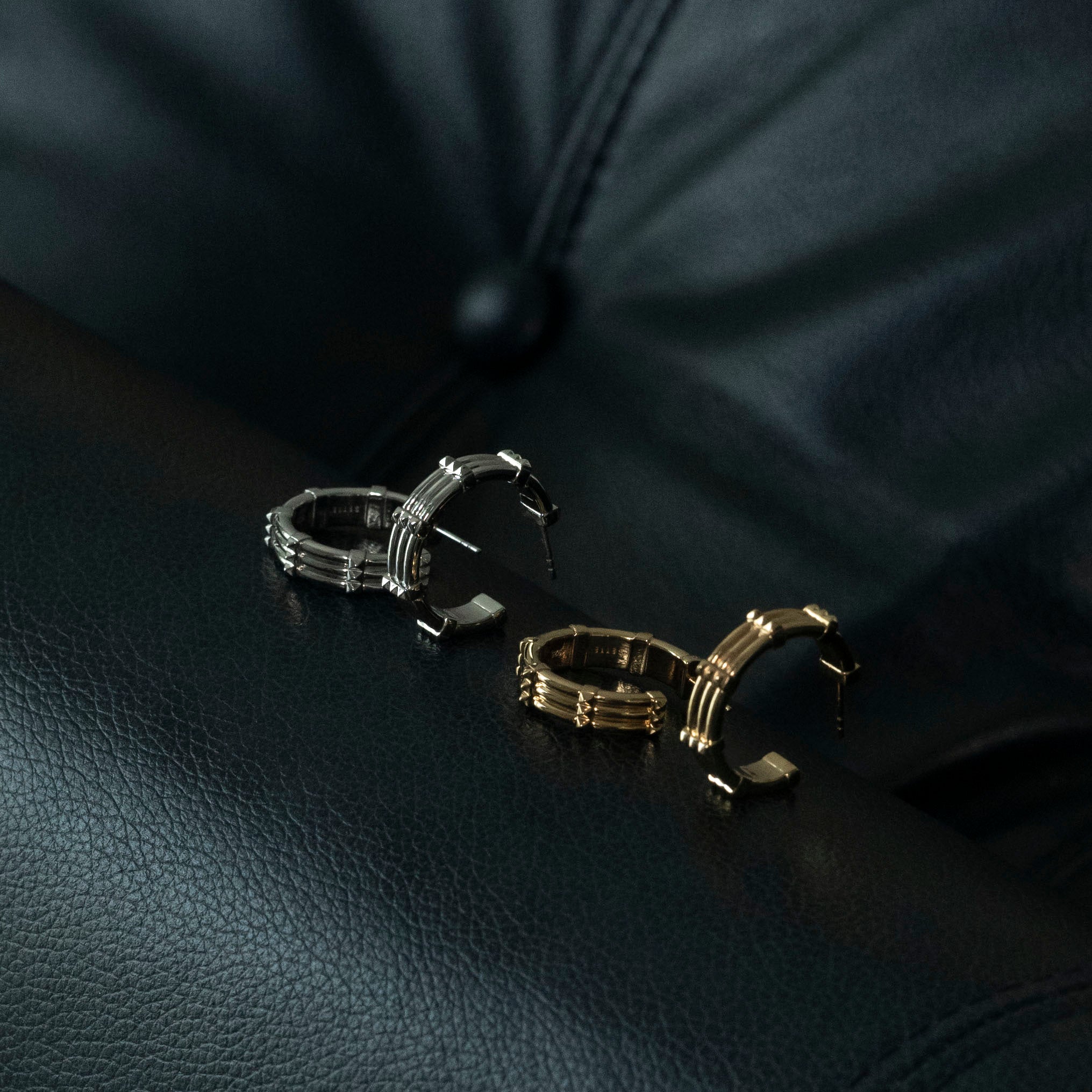 studio sette gold and silver large hoops with stud detailing flatlay on navy leather sofa