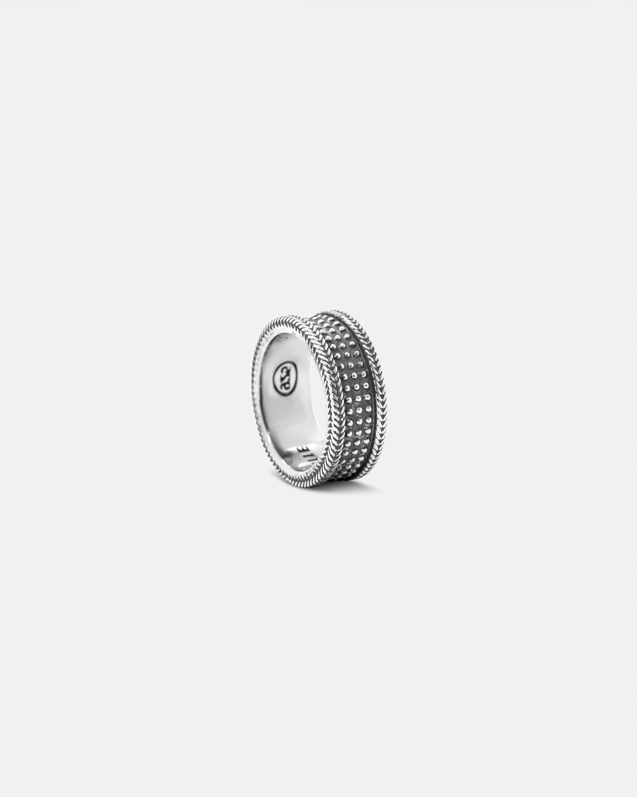 A silver ring with a textured surface and a polished finish, on a white background by studio sette