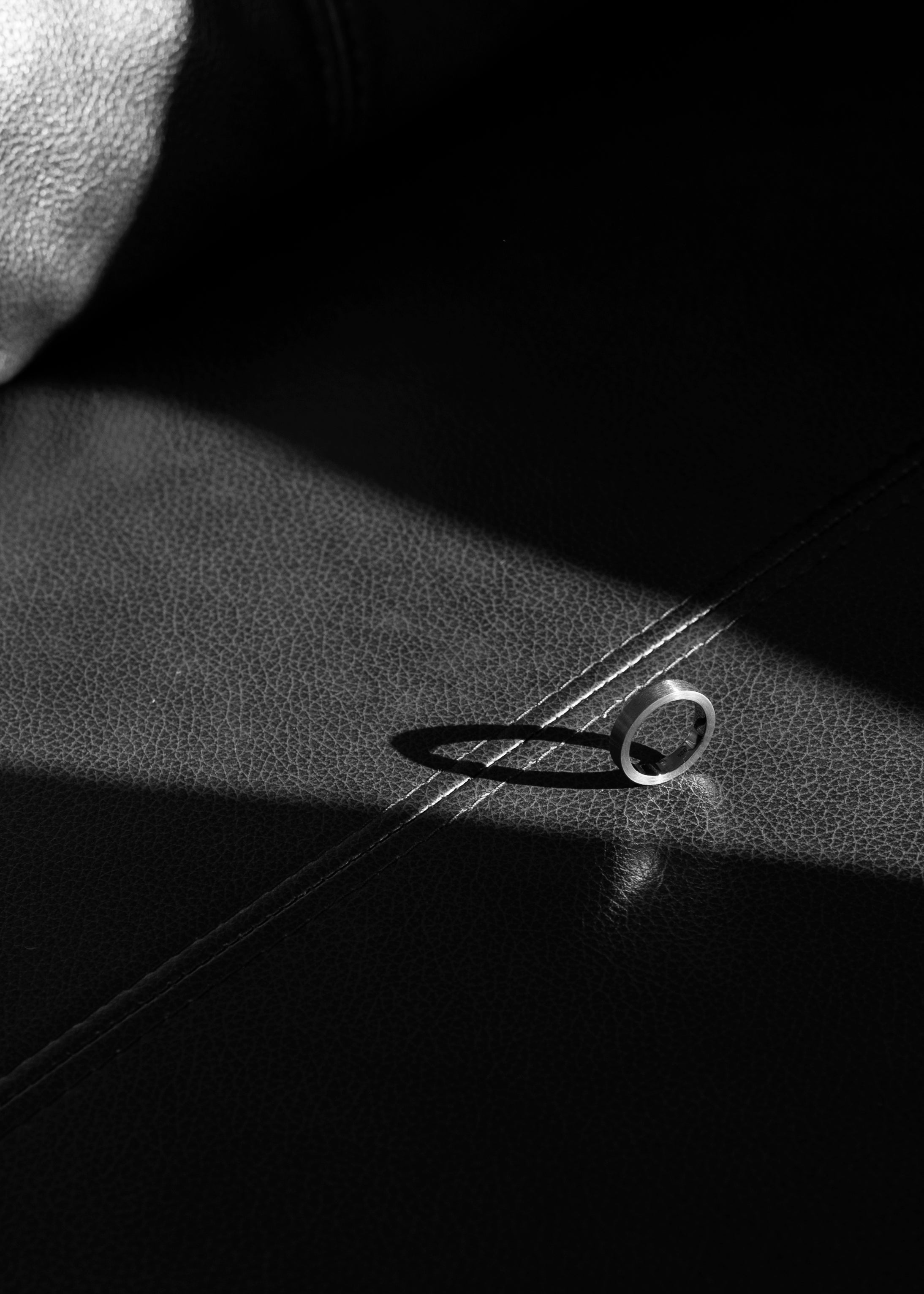unisex silver band ring on a textured leather surface monochrome