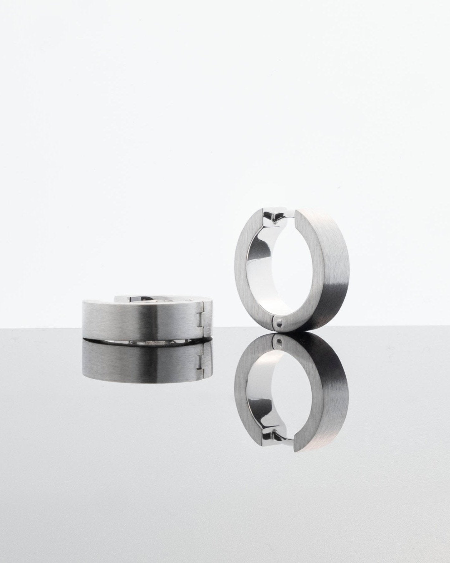 unisex silver earring hoops brutalist design reflecting on light grey background