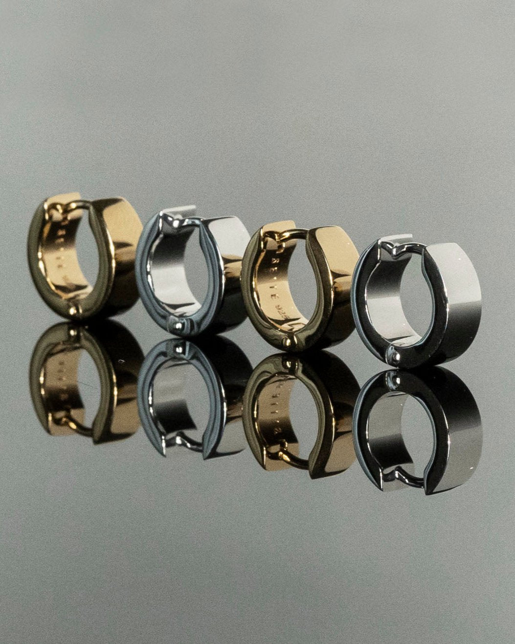 small gold and silver hoops reflecting on grey mirror surface