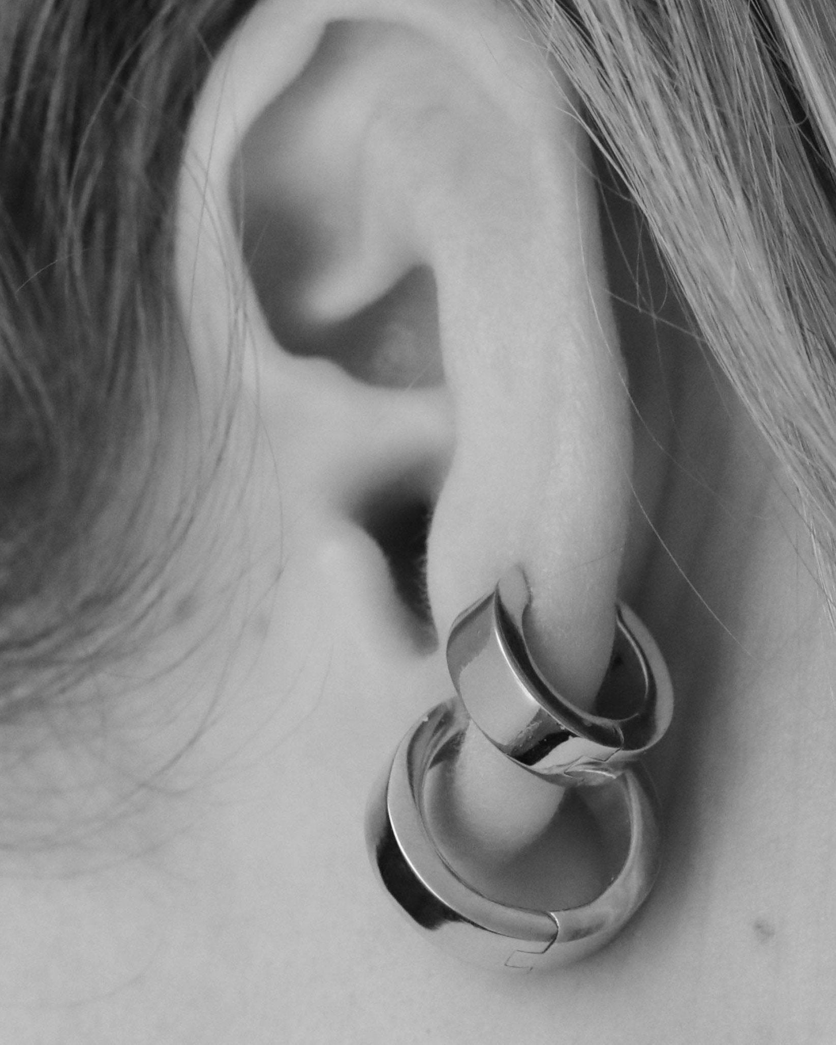 closeup of medium and small hoop earrings on ear in monochrome