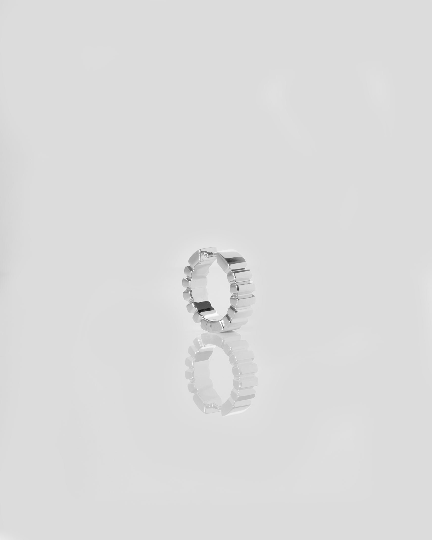 unisex silver hoop reflecting on light grey mirror surface