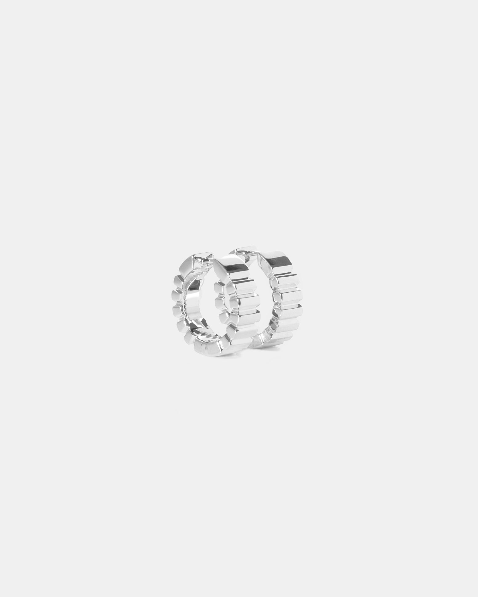 pair of unisex silver earrings with ridged detail on white background