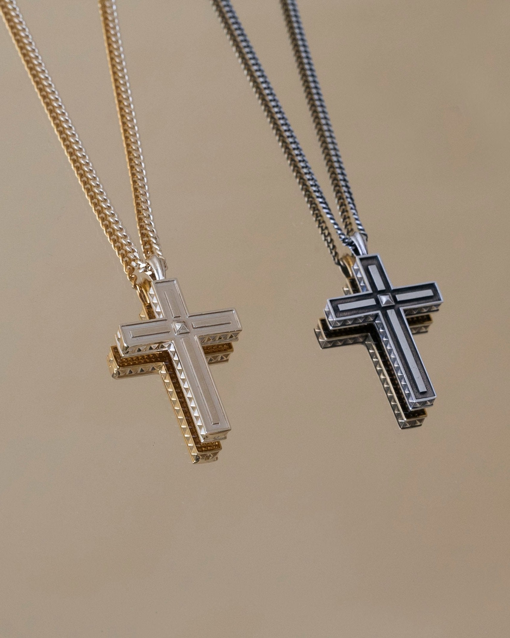two cross pendants reflecting on gold mirror surface