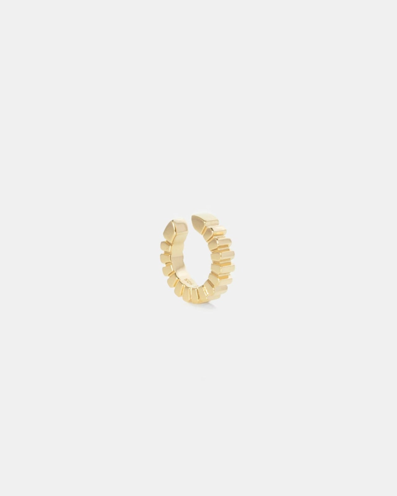 gold ear cuff with ridged edges on white background by studio sette