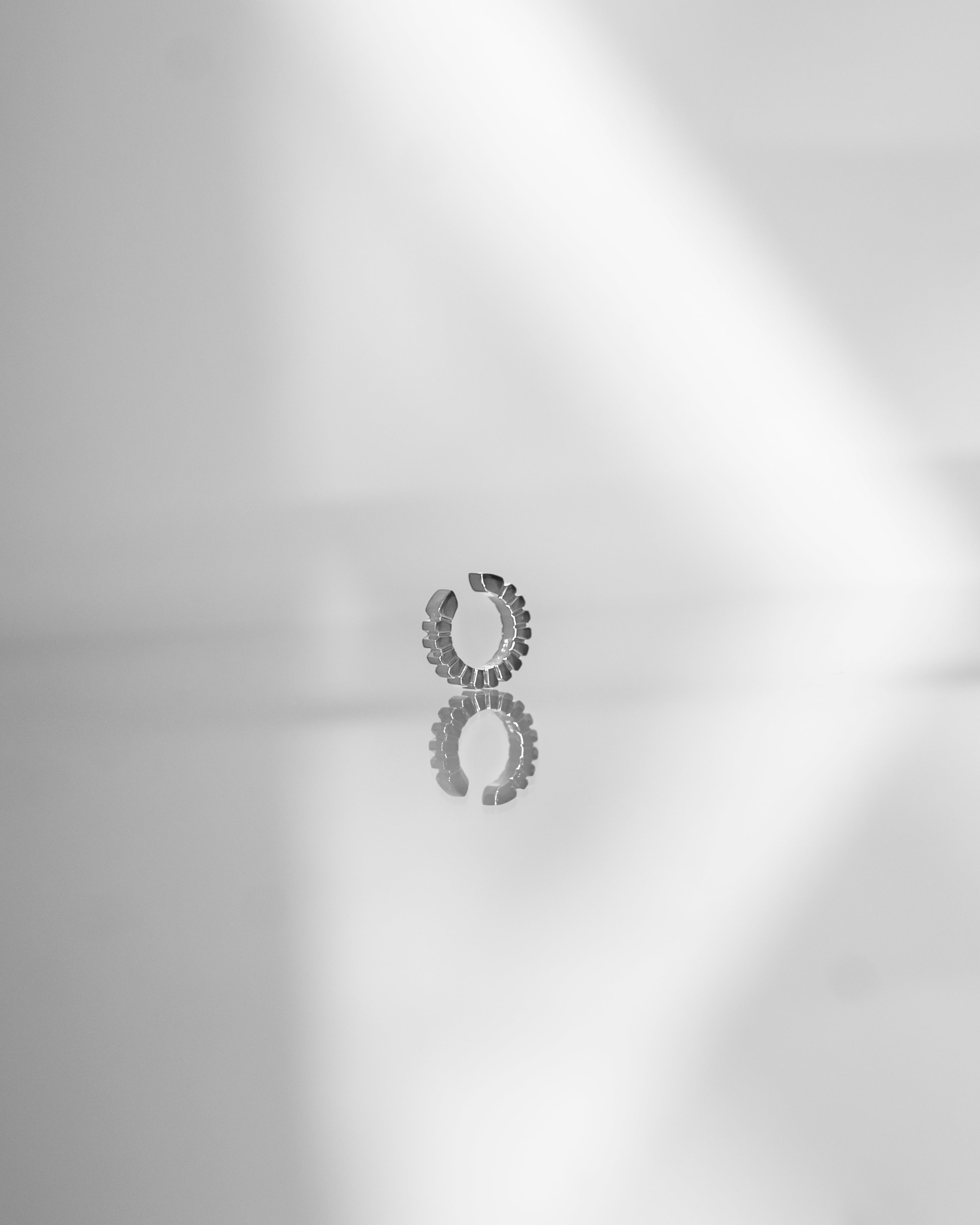 silver ear cuff reflecting on a light grey surface