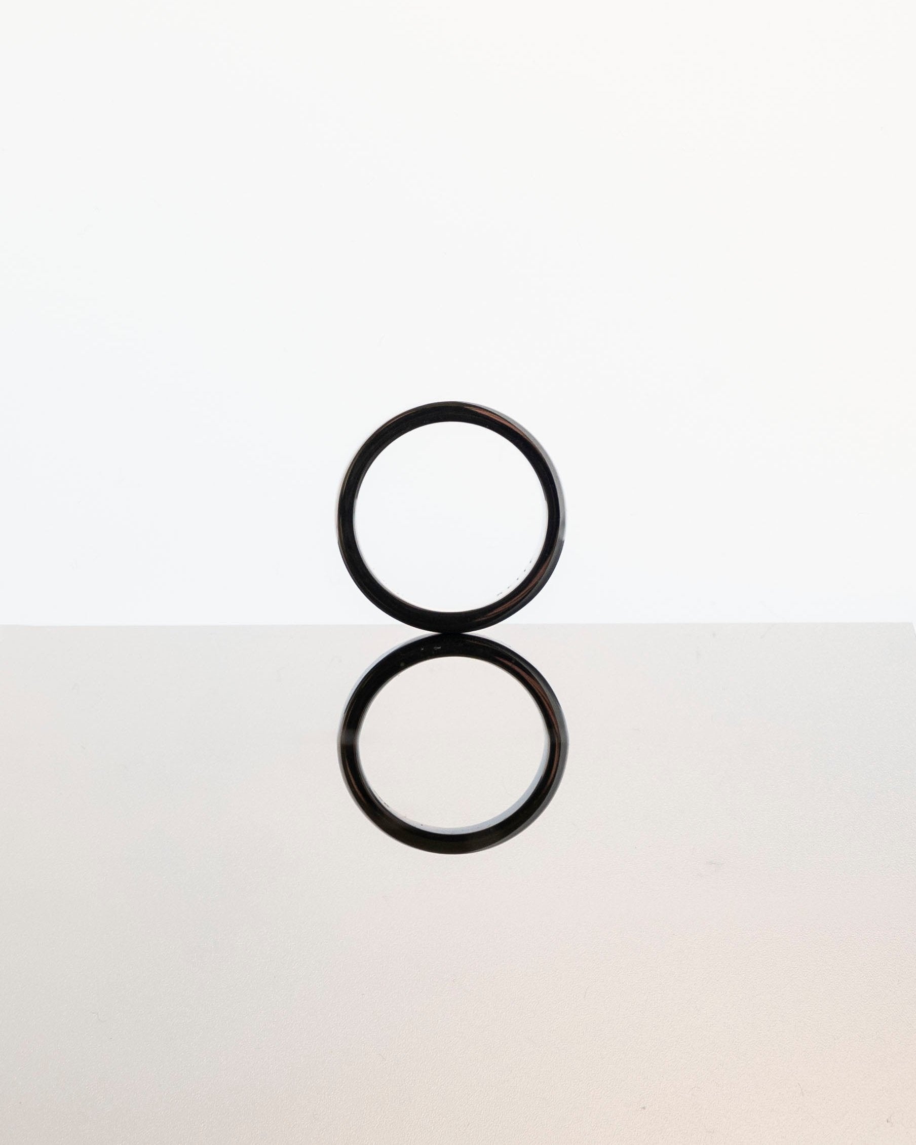 simple band ring reflecting on mirrored grey surface