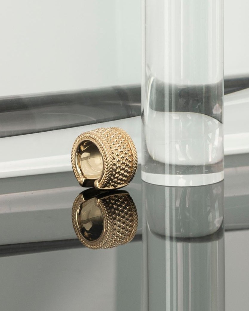 chunky gold ear cuff on grey mirror surface