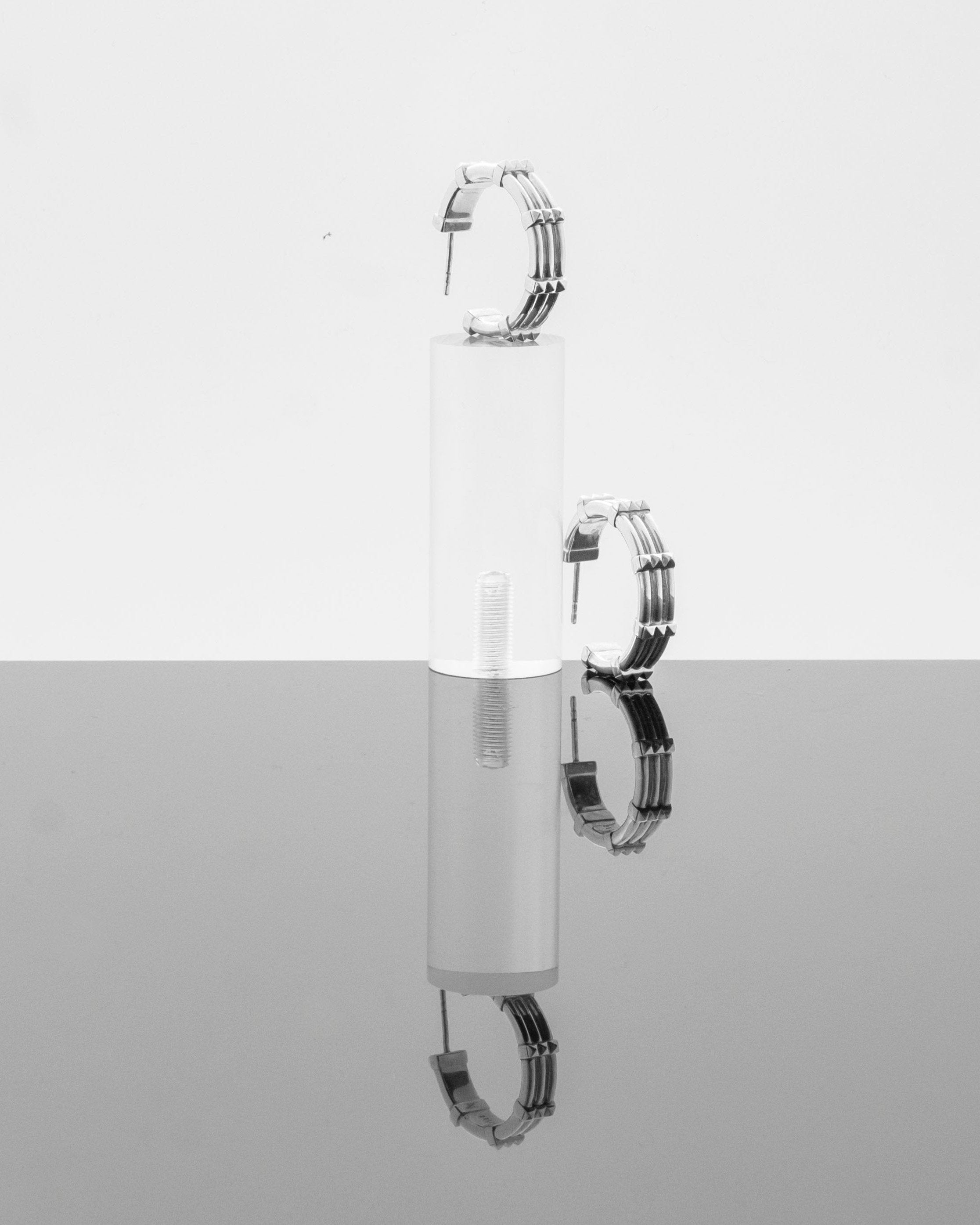 studio sette large hoop earring on perspex podium reflecting on grey background
