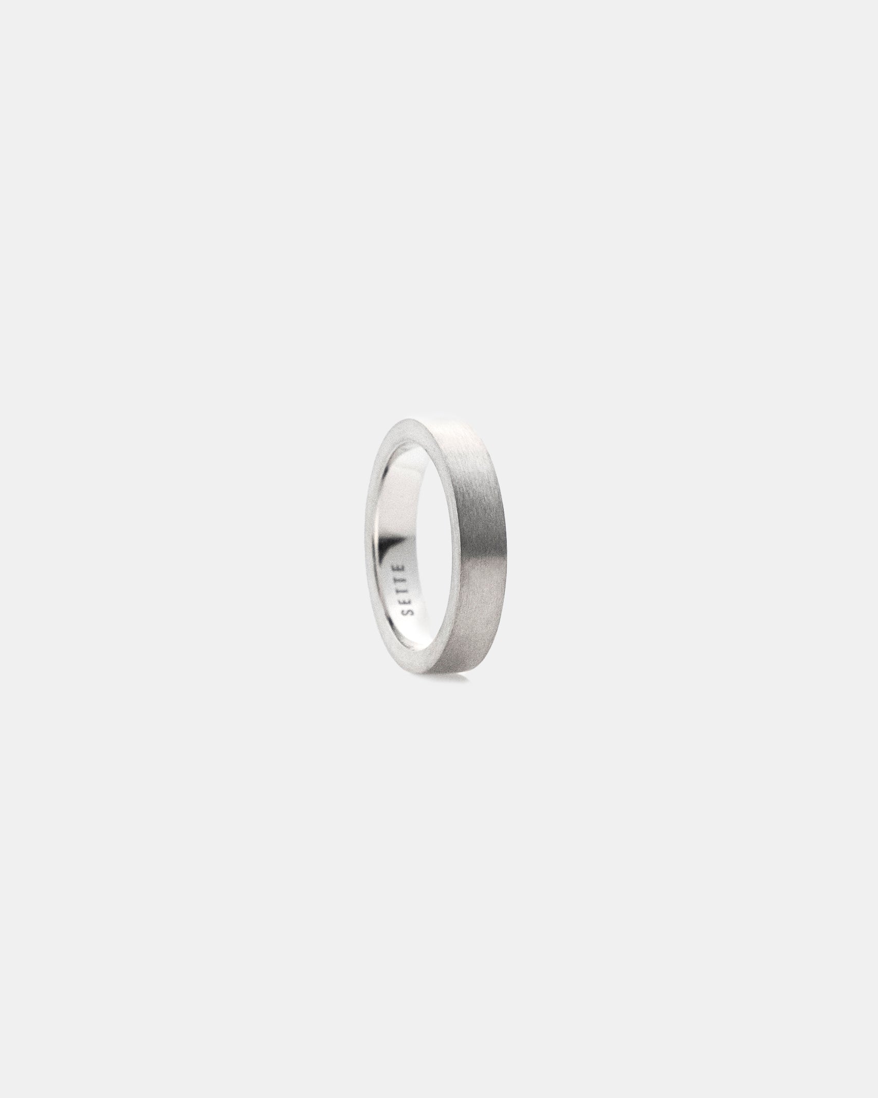 Unisex brushed silver ring on a light gray background