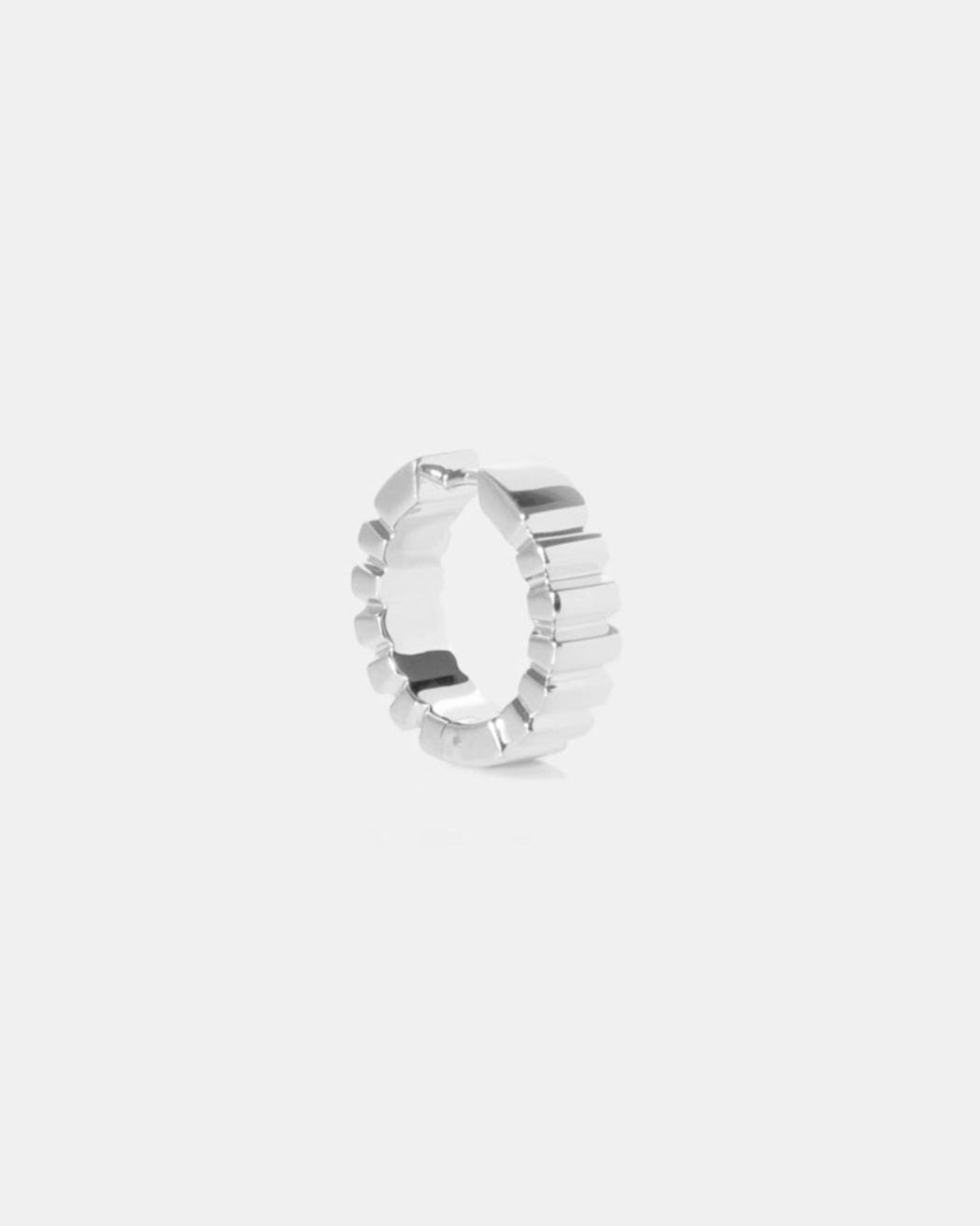 Silver earring with a textured band on a white background by studio sette