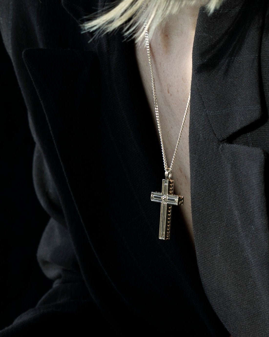 unisex gold cross pendant necklace on model with blazer